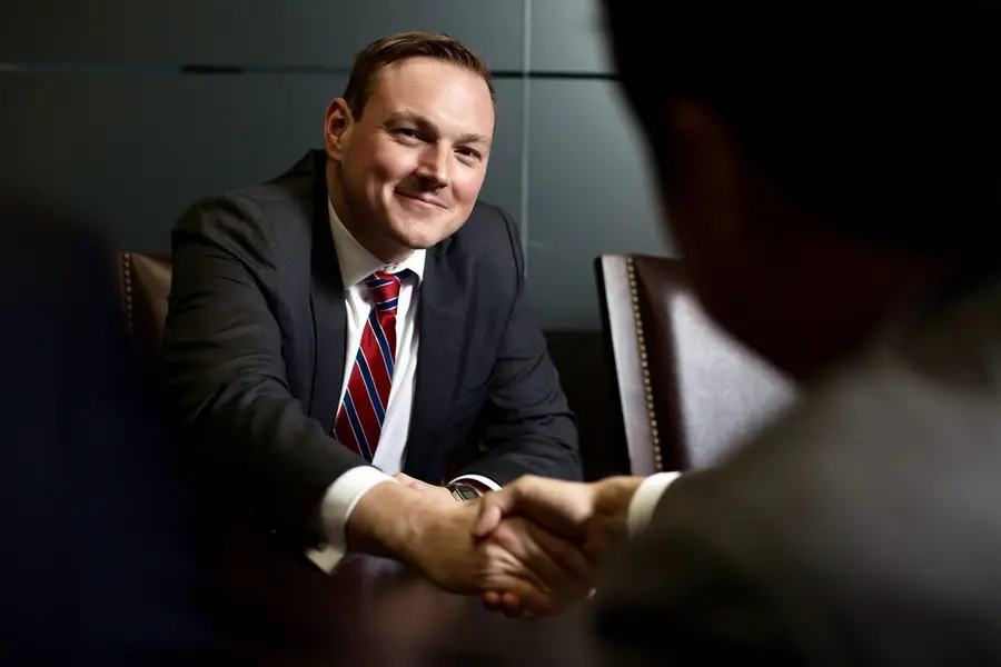 Erik Mitbrodt smiling and shaking hands across a boardroom table